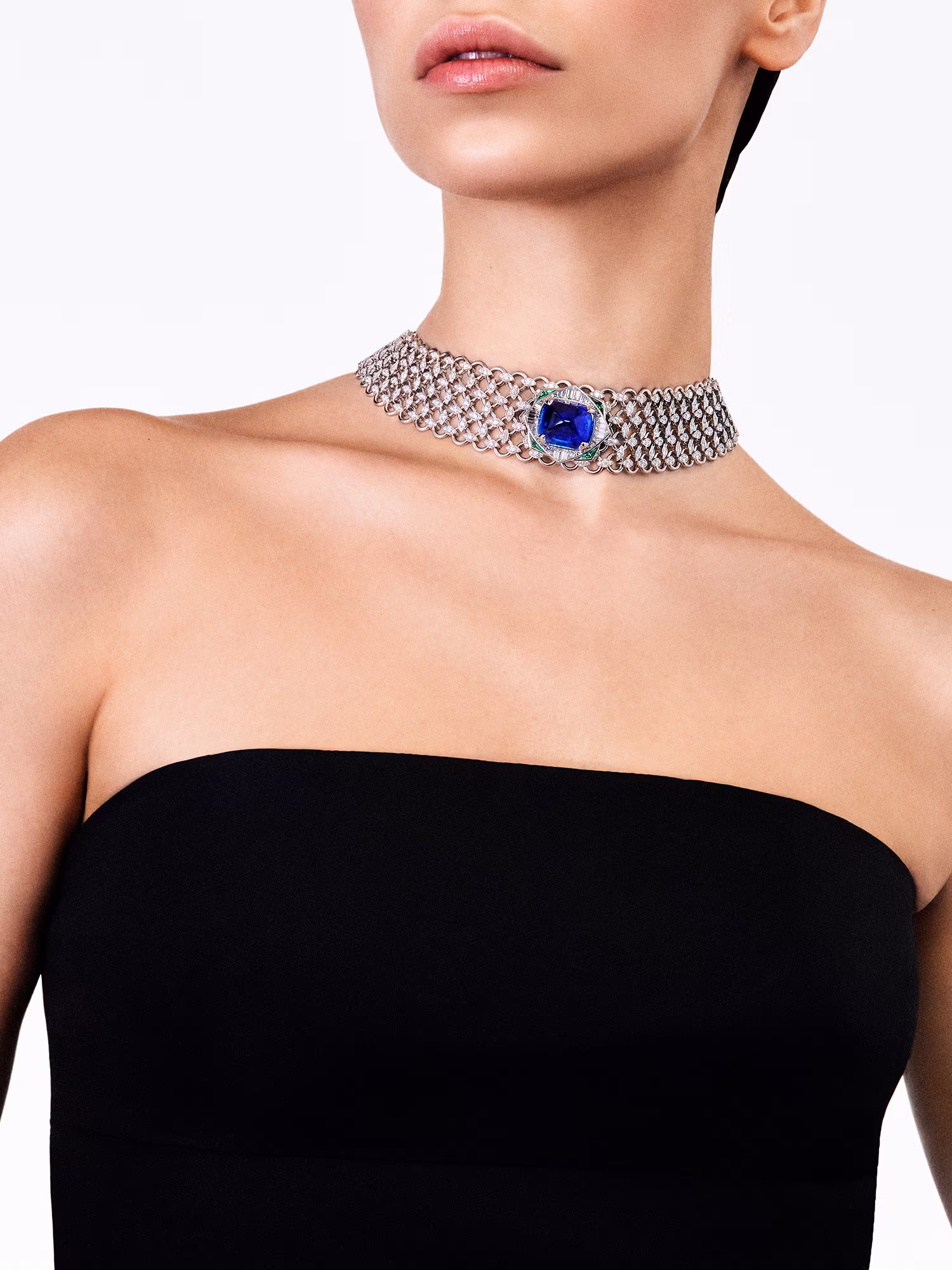 Model wearing a black dress and a diamond choker with a large blue stone in the center.